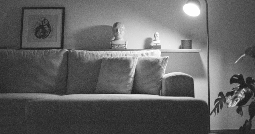 Een schemerige woonkamer met een bank en een brandende staande lamp